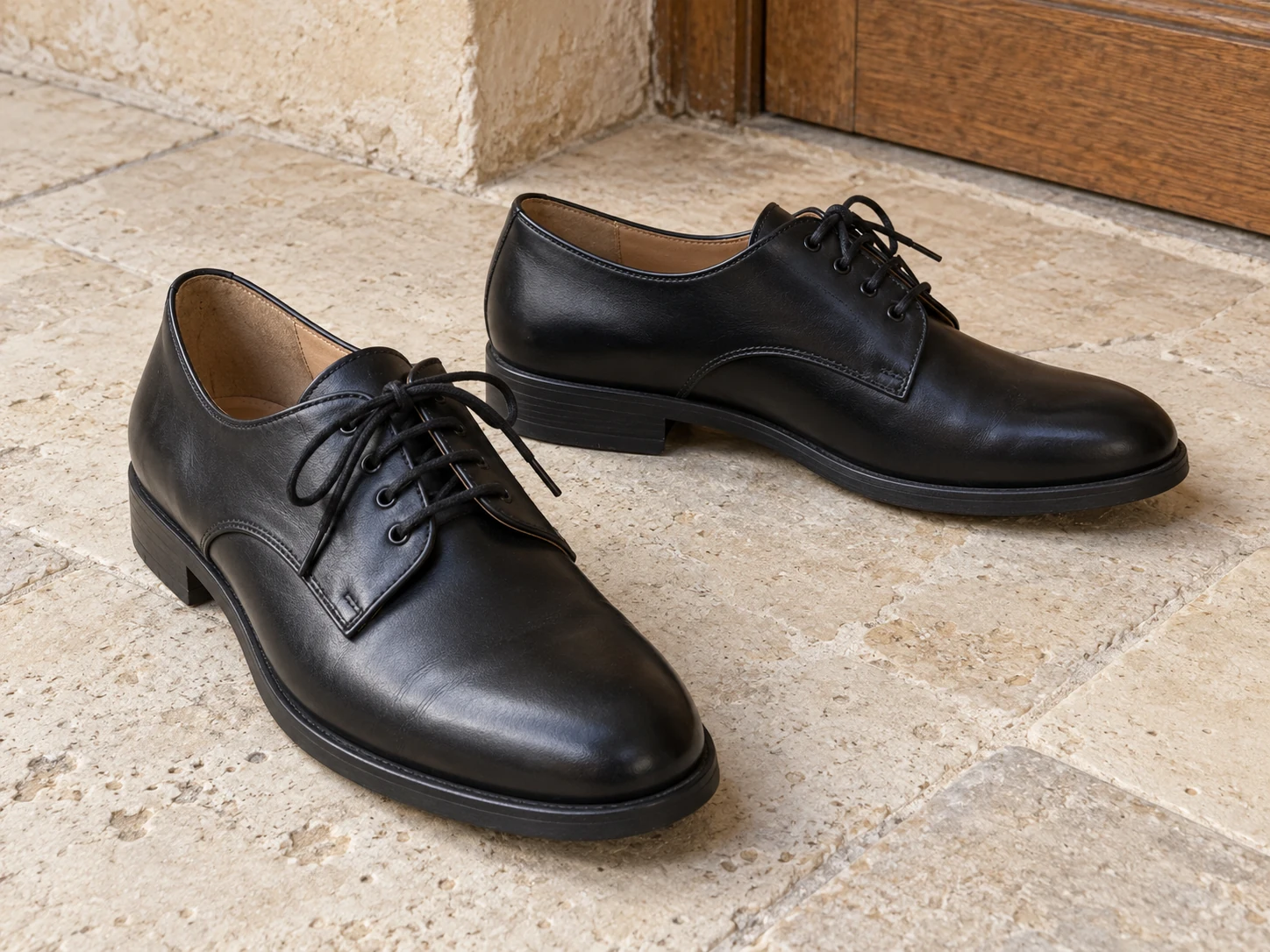 Une paire de derbies noires à lacets, présentant les quartiers du laçage ouvert et un profil à semelle sobre.